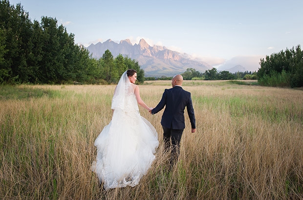 Bride and Groom Walking in Field at Cape Town Wedding Venue by Lauren Kreidemann Photography